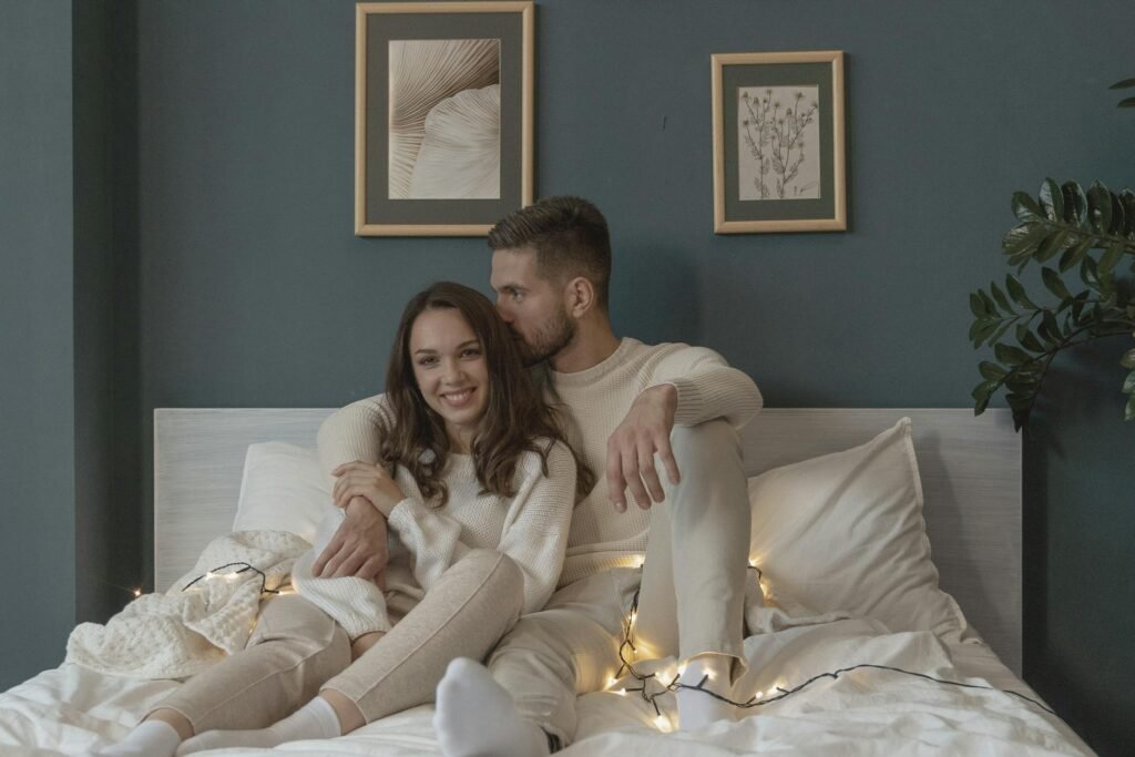 a romantic couple sitting on bed next to each other